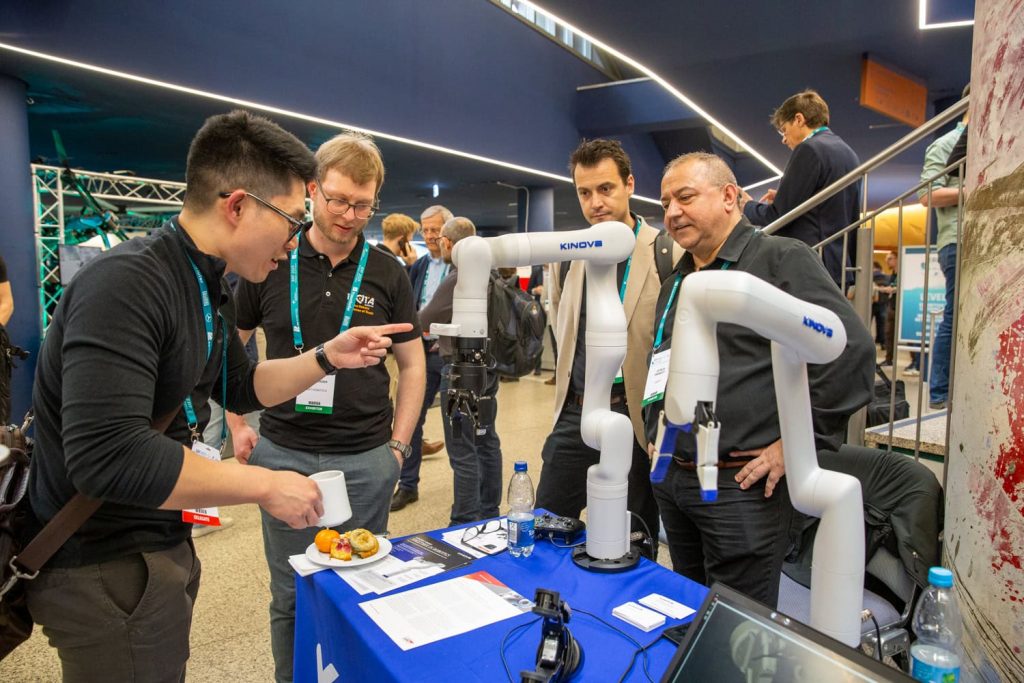 a group of people around a robot arm